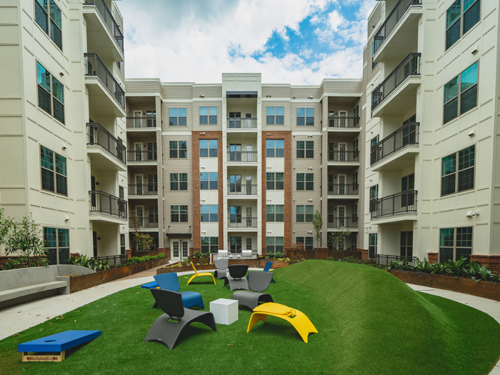 Outdoor green area with seating cornhole games - inner courtyard | Paloma West Midtown | Apartments Near Georgia Tech