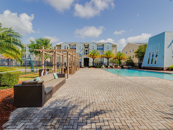 Sun deck with comfortable seating, landscaping with hedges and palm trees, and pool  | Hawks Landing | Apartments in Tampa, FL