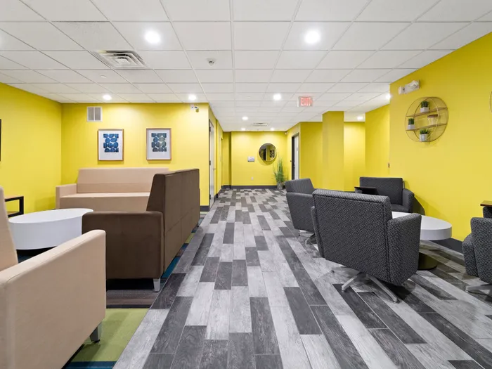 Common area with tables land seating and bright yellow walls at The Printing House | Binghamton Apartments