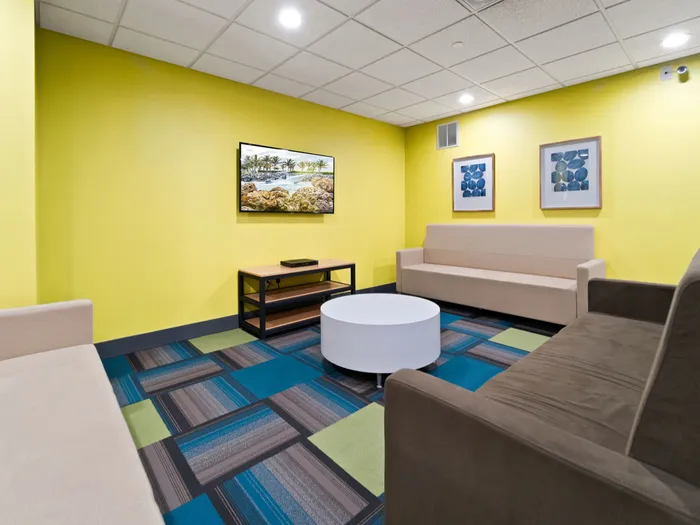 Comfortable seating in front of flat-screen tv in common area at The Printing House | Binghamton Apartments