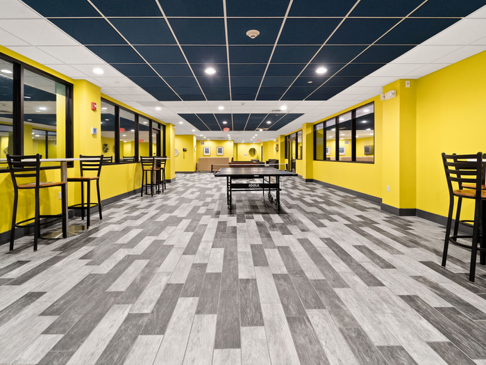 Bright, cheery common area with tables and chairs, ping-pong tableat The Printing House | Binghamton Apartments