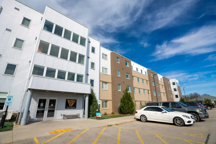 Exterior of building with signage on wall near entrance | 	Tech Village | Student Apartments Appleton