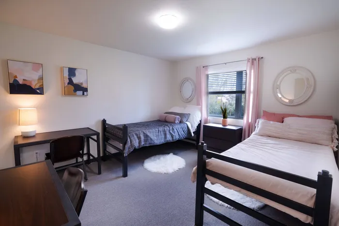 Bedroom with two beds and two desks  in student apartment at Tech Village.