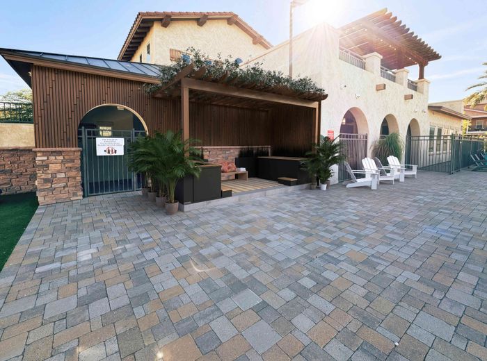 Inviting outdoor patio area with seating, pergola, and sunlit stone flooring.