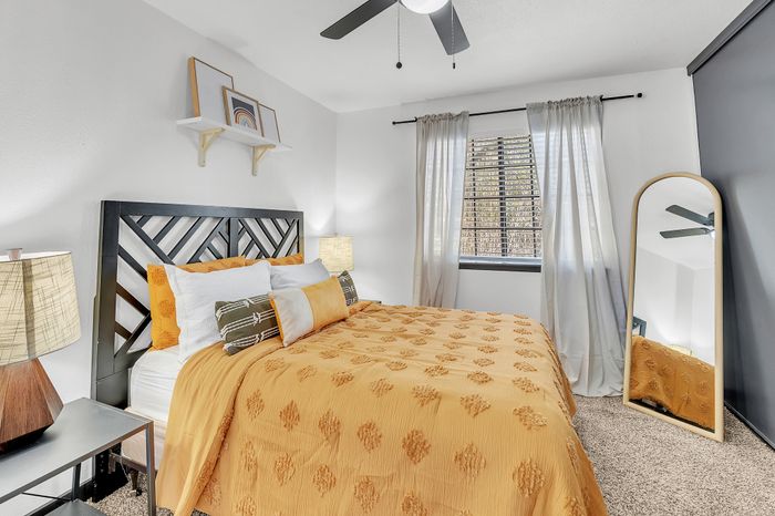 Inviting bedroom with stylish decor, featuring a patterned bedspread, modern lamps, and a large mirror.