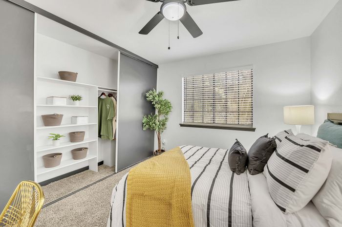 Stylish bedroom with modern decor featuring a cozy bed, open closet, and natural light from a large window.