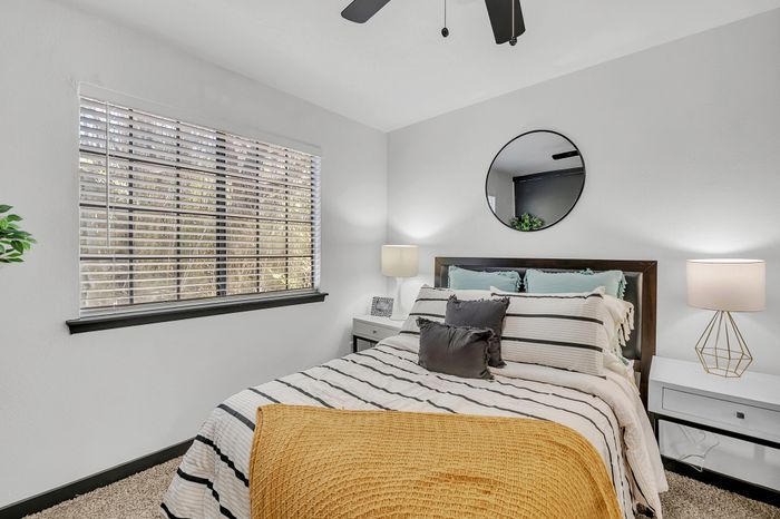 Inviting bedroom with a stylish bed, striped bedding, and a warm yellow throw blanket.
