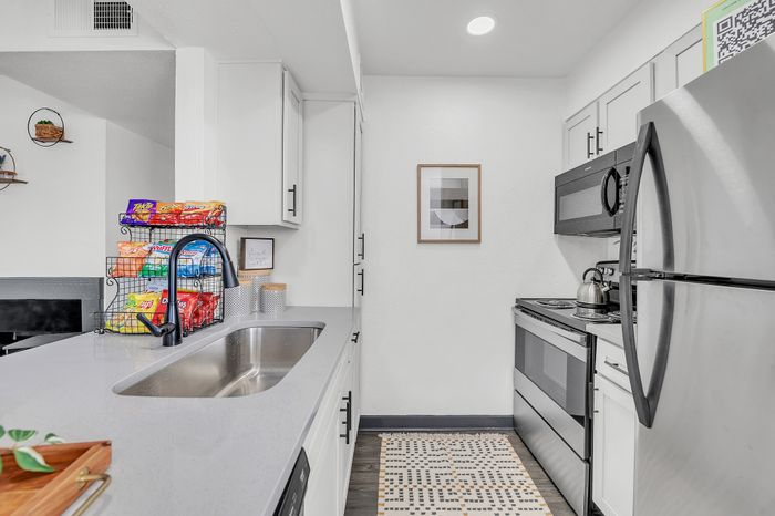 Contemporary kitchen with sleek stainless steel appliances, stylish countertop, and organized storage space.