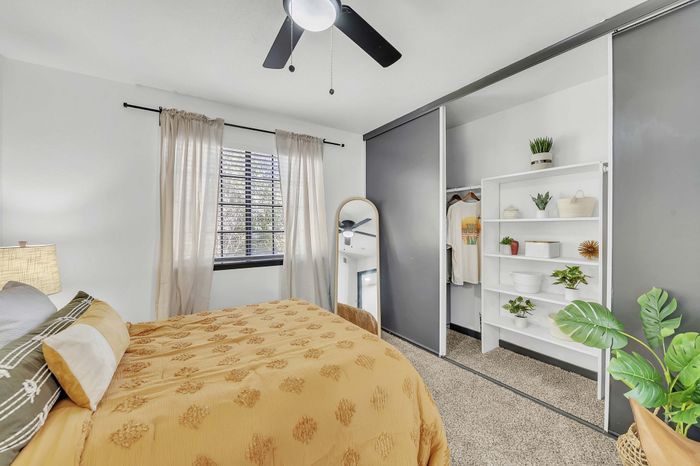 Inviting bedroom with a cozy bed, modern decor, and ample closet space with organized shelving.
