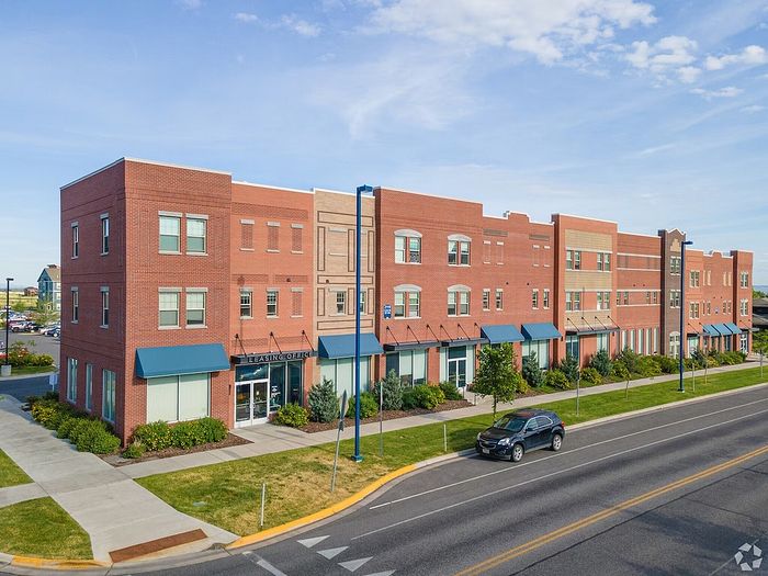 Charming red-brick apartment complex with modern design, blue awnings, and lush landscaping, perfect for urban living.