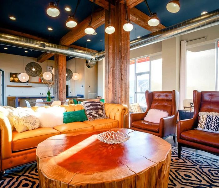 Chic industrial-style living room with vibrant leather seating, rustic wood accents, and ambient pendant lighting.