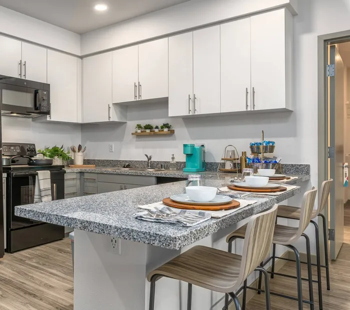 Kitchen with white cabinetry and island  at Merced Station apartments
