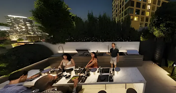 Modern outdoor kitchen at night with people enjoying a stylish dining area, set against a backdrop of lush greenery and urban architecture.