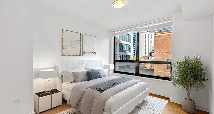 Bright and modern bedroom with a cozy double bed, stylish decor, large window with city views, and a touch of greenery.