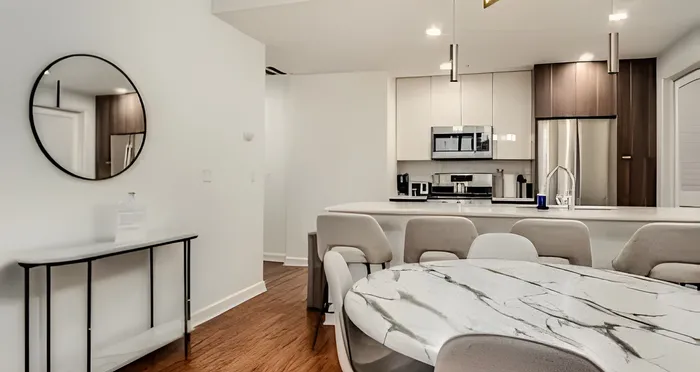 Sleek modern kitchen with a marble dining table, elegant seating, and stylish mirror accent.