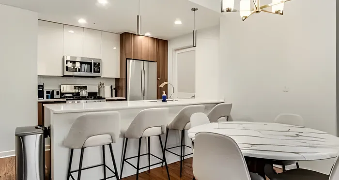 Modern kitchen with sleek stainless steel appliances, elegant island seating, and stylish lighting fixtures, perfect for entertaining.