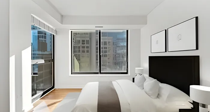 Bright, modern bedroom with large windows showcasing city views and stylish decor.