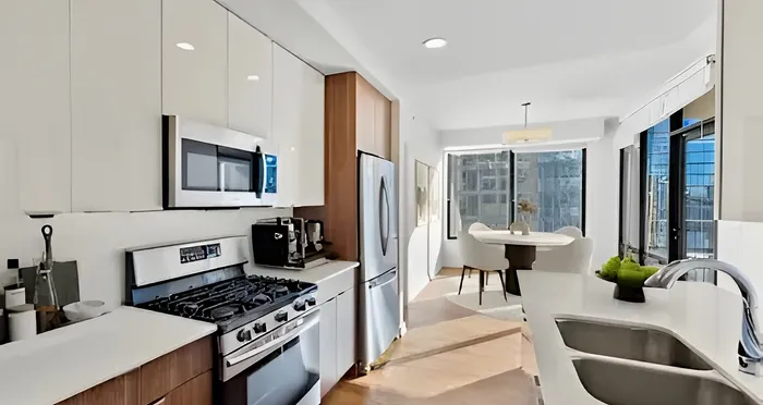 Chic modern kitchen with sleek appliances, ample cabinetry, and bright dining area with large windows.