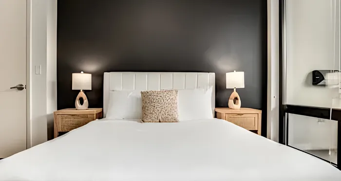 Elegant bedroom with a plush white bed, stylish bedside lamps, and sophisticated black accent wall.