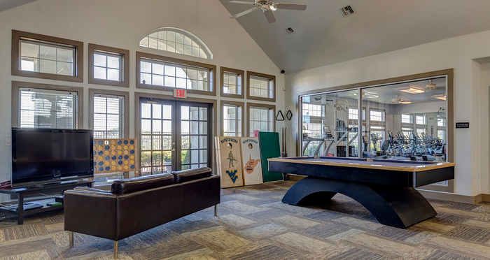Chic recreational room with large windows, featuring a comfortable TV lounge, pool table, and access to a modern fitness center.