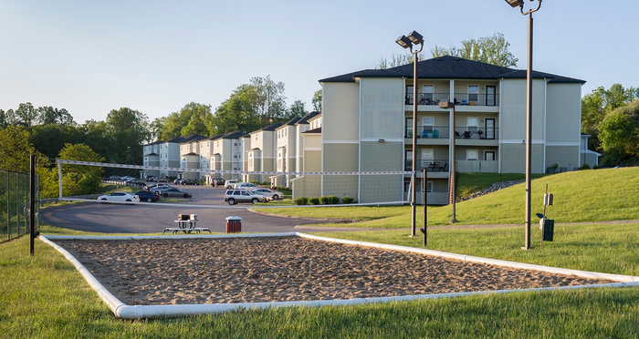 Charming apartment complex surrounded by lush greenery, featuring outdoor sports facilities and ample parking space.