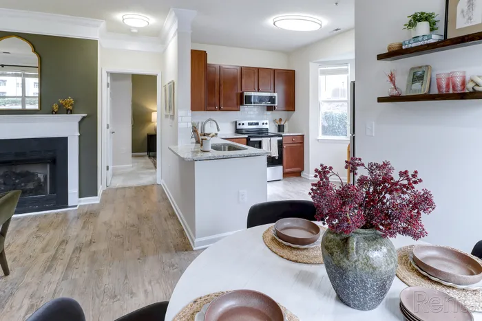 Elegant living area featuring a cozy fireplace, modern kitchen with granite countertops, and stylish dining setup.