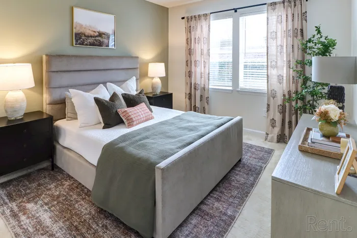 Stylish bedroom with a plush bed, elegant decor, and bright natural light.