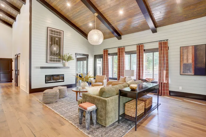 Chic living room with vaulted wood ceilings, elegant fireplace, and natural light pouring through large windows, perfect for relaxation and entertainment.