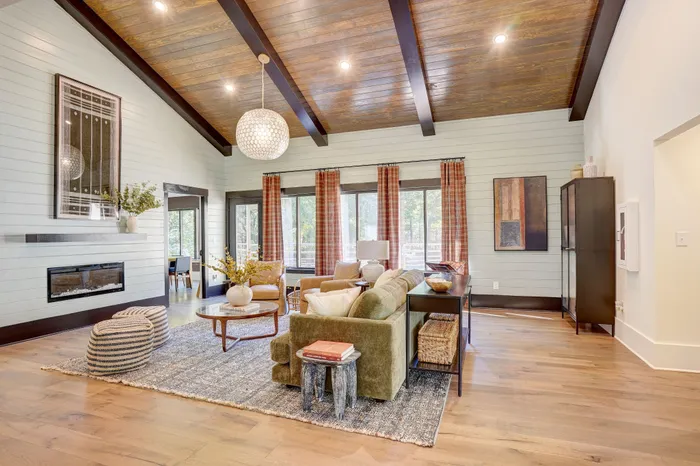 Inviting living room with vaulted wooden ceiling, modern fireplace, and abundant natural light from large windows, perfect for cozy gatherings.
