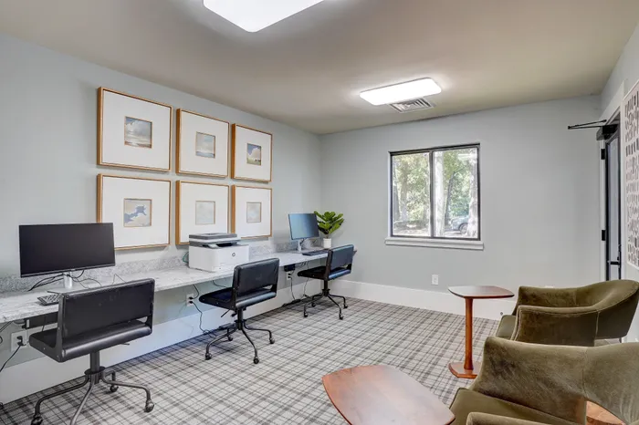 Modern co-working space with sleek desks, minimalist decor, and natural light through large windows, perfect for productivity.