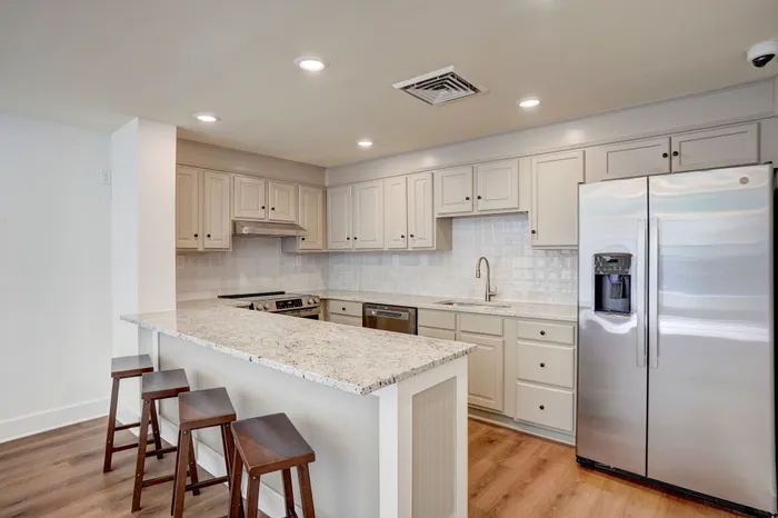 Modern kitchen with elegant granite countertops, stainless steel appliances, and cozy bar seating.