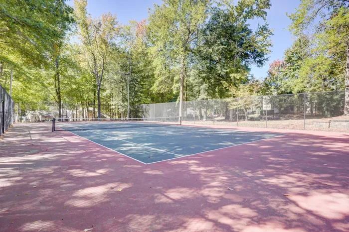 Inviting outdoor tennis court set amidst lush green trees, perfect for sports enthusiasts and nature lovers.