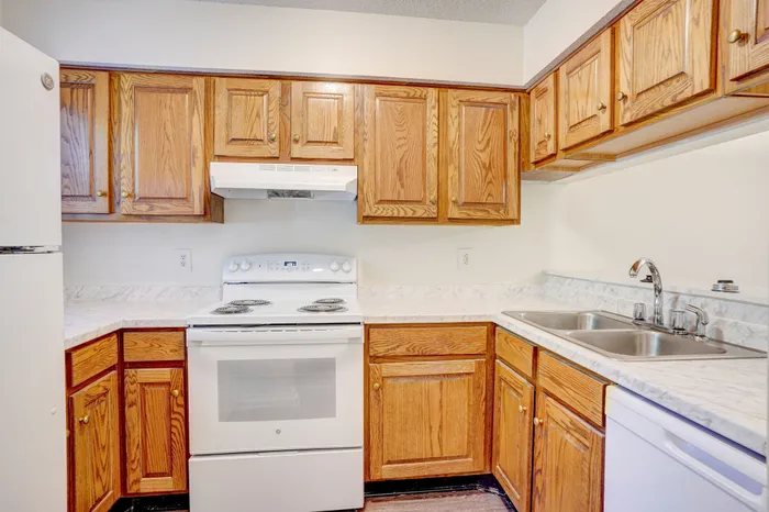 Charming kitchen with warm wooden cabinetry, marble countertops, and modern appliances offering a cozy cooking space.