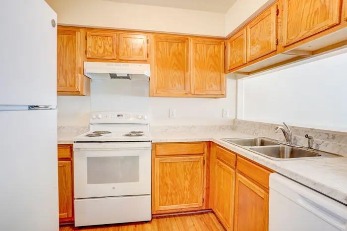 Inviting kitchen with warm wooden cabinets, sleek countertops, and modern appliances offering a cozy cooking space.