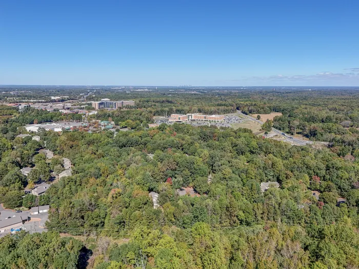 Scenic aerial view of a lush, green suburban landscape with a blend of residential and commercial buildings, inviting a tranquil living environment.