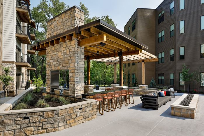 Weatfield Village Apartment Courtyard Grilling Lounge Fire Pit Seating in Topeka, KS. Gather around the fire pit in the courtyard grilling lounge area at Wheatfield Village Apartments, enjoying a cozy and inviting atmosphere for outdoor relaxation and dining.