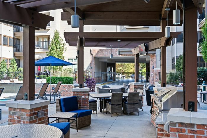 Outdoor Conversation Seating under Pergola and Gas Grills - An outdoor seating area under a pergola with gas grills, offering residents an inviting spot for outdoor gatherings and barbecues.