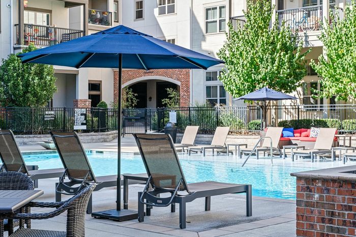 Resort Style Pool with Lounge Seating and Umbrella Landscape - A resort-style pool surrounded by comfortable lounge seating and umbrellas, creating a perfect setting for leisure and enjoyment.
