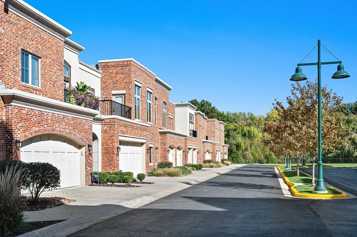 Exterior Image Showcasing Attached Enclosed Garage, Beautiful Greenery, and Balconies - A view of the exterior showcasing townhomes with attached enclosed garages, lush greenery, and charming balconies