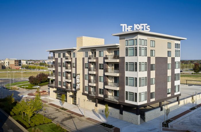 Modern apartment building exterior at The Lofts at City Center in Lenexa" Caption: "Contemporary design meets city center convenience