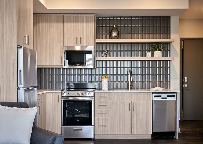 Modern kitchen with quartz countertops, stainless appliances, and designer tile backsplash