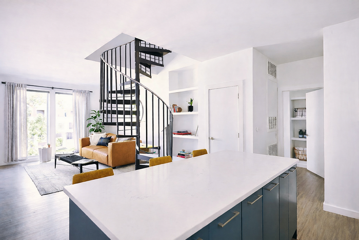 Modern apartment living room with spiral staircase, chic sofa, and bright open space, perfect for cozy gatherings.