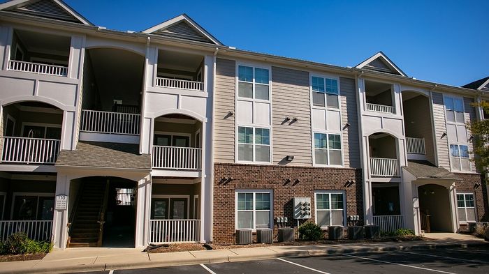 Modern apartment complex with stylish balconies and a vibrant exterior in a sunny neighborhood.