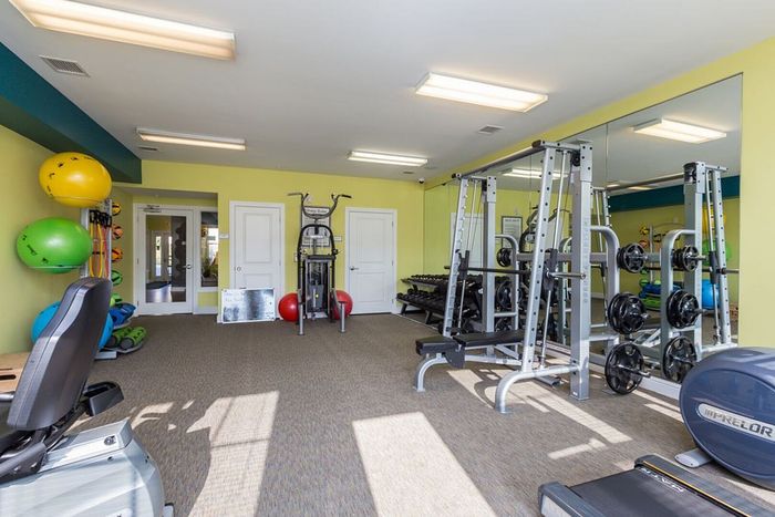 Bright and inviting fitness room featuring modern exercise equipment, vibrant workout balls, and spacious mirrored walls.
