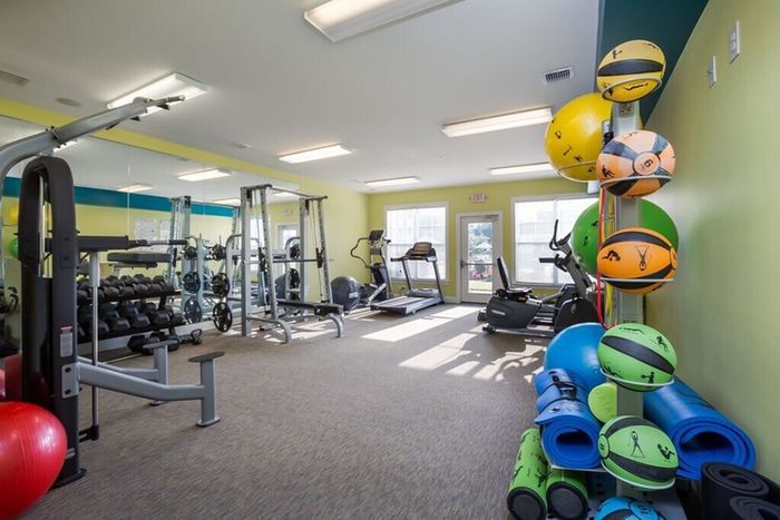 Bright and modern gym with state-of-the-art fitness equipment, vibrant yoga balls, and padded flooring for comfort.