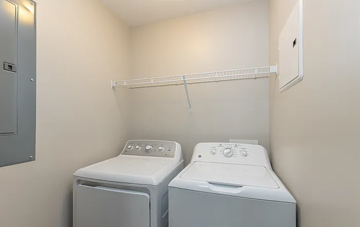 Modern laundry room with sleek washer and dryer, enhanced by ample shelving and neutral tones.