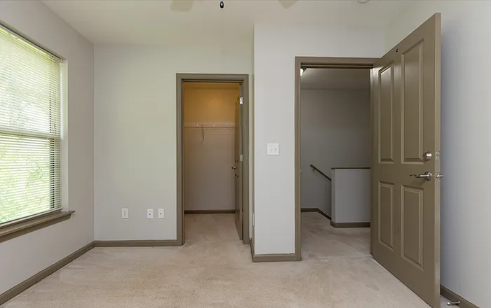 Bright and inviting bedroom with plush carpet, featuring a sunlit window, walk-in closet, and bedroom entrance for easy access.