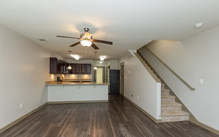 Modern open-concept living area with sleek kitchen, granite countertops, and elegant staircase, perfect for stylish living.