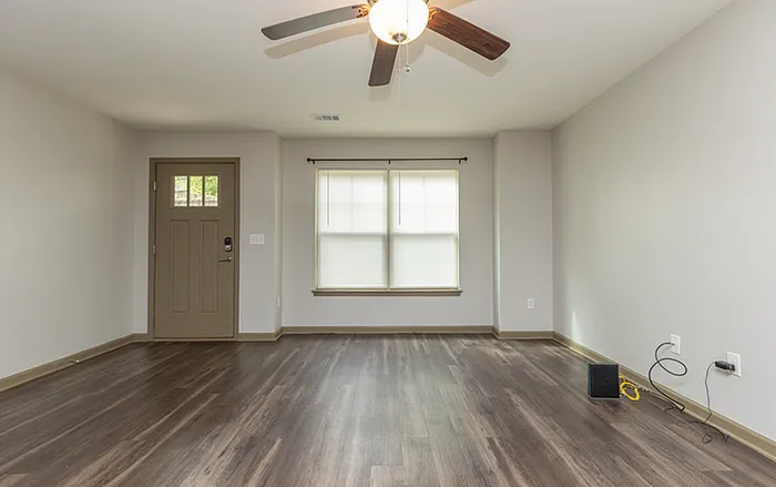 Bright and welcoming living room with elegant hardwood floors and natural light streaming through large windows, perfect for relaxation.