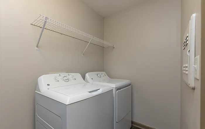 Modern laundry room with energy-efficient washer and dryer, featuring sleek white appliances and convenient shelving.